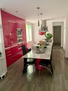 una cocina con armarios rojos y una mesa con sillas. en CasaCec, en Alicante