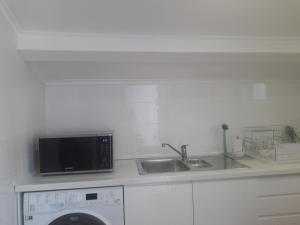 uma cozinha com máquina de lavar e pia em Sesimbra Beach Fonte House em Sesimbra