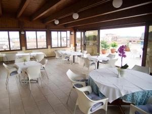 ein Restaurant mit weißen Tischen und Stühlen und Fenstern in der Unterkunft Hotel Tessarin in Taglio di Po