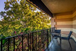 a balcony with two chairs and a table at Hotel Pepper Tree Boutique Kitchen Studios - Anaheim in Anaheim