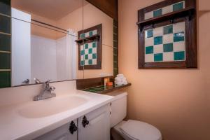 a bathroom with a toilet, sink and mirror at Hotel Pepper Tree Boutique Kitchen Studios - Anaheim in Anaheim