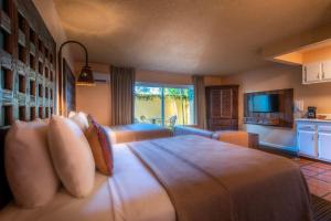 a bedroom with a large bed and a television at Hotel Pepper Tree Boutique Kitchen Studios - Anaheim in Anaheim