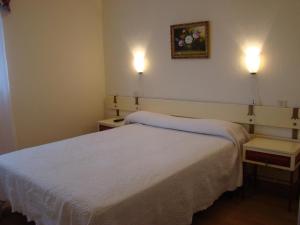a bedroom with a white bed and two lights on the wall at Pensión Mariaje in Celorio