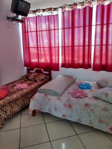 duas camas num quarto com cortinas vermelhas em Hospedaria Piramide Por Do Sol em São Tomé das Letras