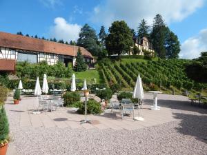 a patio with tables and chairs and white umbrellas at Wein Lodge Durbach - Schlossblick in Durbach