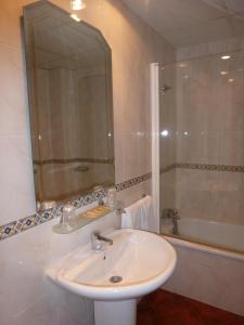 a white bathroom with a sink and a tub at Hostal Restaurante Asador Pañart in Bielsa