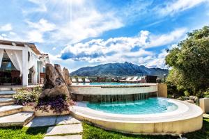 a swimming pool in a yard with mountains in the background at Cento Ulivi B&B in Golfo Aranci