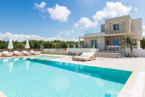 a villa with a swimming pool in front of a house at Rosmerta Villa, Chic & Prestigious, By ThinkVilla in Perama
