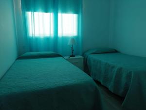 um quarto azul com duas camas e uma janela em Duplex Belmaco - Casitas las Abuelas em Santa Cruz de la Palma