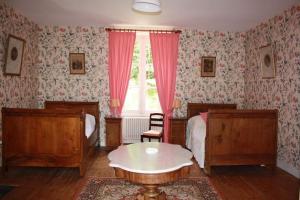 a bedroom with two beds and a table and a window at DOMAINE de la BORLIERE in Fenioux +5 photos