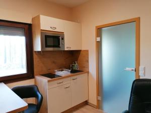 a small kitchen with a microwave and a door at Apartment GNUBBEL am Wald in Weißwasser