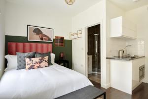 a bedroom with a white bed and a kitchen at Sonder St Johns Garden in London