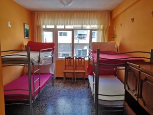 a room with three bunk beds and a window at Albergue Por Fin in Fisterra