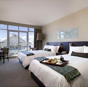 a hotel room with two beds and a table at The Sidney Pier Hotel & Spa in Sidney