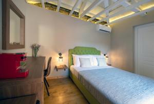 a bedroom with a bed with a green headboard and a dresser at Metis Athens Suites in Athens