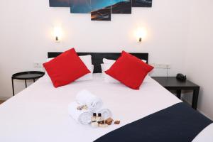 a white bed with red pillows and towels on it at Inbar Hotel in Arad