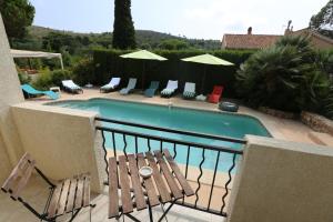 a swimming pool with chairs and umbrellas on a balcony at La Bastide des Pins in Le Pradet
