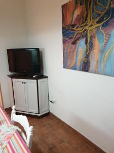 um quarto com uma televisão e um quadro na parede em Casa Marta em Palermo