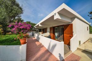 Residence Palm Beach في بيسكيتشي: منزل أبيض مع زهور وردية في الفناء