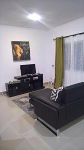 uma sala de estar com um sofá preto e um piano em Ibex Heights em Lusaka