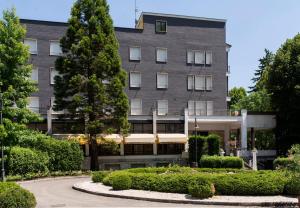 un gran edificio gris con arbustos delante de él en Hotel Salus, en Sant Andrea Bagni