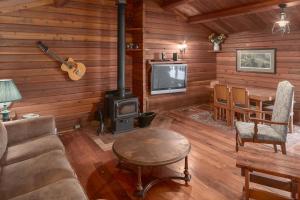 sala de estar con estufa de leña y TV en Creekside Cabin en Fairmont Hot Springs