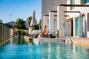 una mujer sentada en una silla junto a una piscina en Hotel Boutique Aroma de Mar, en Chiclana de la Frontera