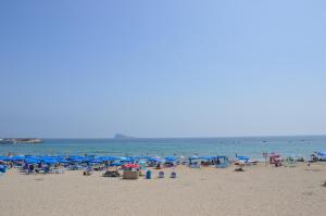 plaża z niebieskimi parasolami i ludzie na plaży w obiekcie Marconi Anis Primera Linea w mieście Benidorm