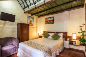 a bedroom with a bed and a chair and a television at Hotel Muisca in Bogotá