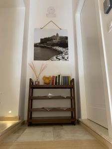ein Bücherregal im Flur mit einem Bild an der Wand in der Unterkunft Sant'Eufemia Rooms Self Check in in Vieste