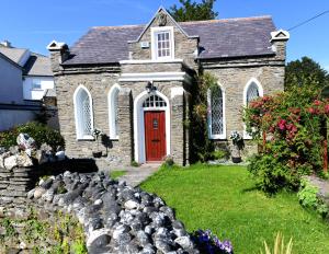 eine Kirche mit einer roten Tür und einem Hof mit Steinen in der Unterkunft Welch House in Douglas