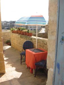 una mesa con 2 sillas y una sombrilla en el balcón en 400YR Farmhouse in Xaghra Gozo - Separate Rooms, en Xagħra