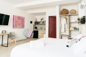 a white bedroom with a white bed and a desk at dewl estudios & residences : THE KAHLO in Playa del Carmen