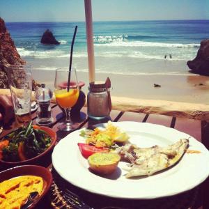 a table with a plate of food on the beach at Mel&Laranja in Alvor