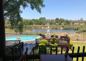 a swimming pool with a river in the background at Sabie River Bush Lodge in Hazyview