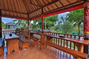 un pabellón con bancos de madera, mesas y árboles en Mamaras Guest House, en Nusa Penida