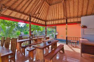 restauracja z drewnianymi stołami i ławkami w pawilonie w obiekcie Mamaras Guest House w mieście Nusa Penida