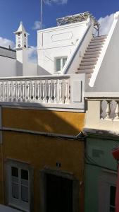 a building with a white balcony and a clock tower at Casa Magica in Olhão