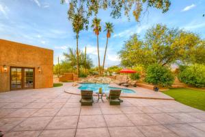 un patio trasero con piscina, sillas y árboles en Hacienda Panorama Estate, en Tucson