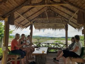eine Gruppe von Frauen, die an einem Tisch in einem Pavillon sitzen in der Unterkunft Kham Ecolodge in Chiang Saen