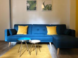 un canapé bleu avec des oreillers jaunes et une table dans l'établissement City'IN Appart, à Carcassonne