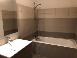 La salle de bains est pourvue d'une baignoire, d'un lavabo et d'un miroir. dans l'établissement City'IN Appart, à Carcassonne