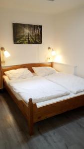 a bedroom with a wooden bed with white sheets at Hamburg/Berlin Hamburg App. 106 in Großenbrode