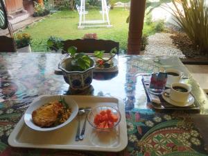 einen Tisch mit einem Teller mit Lebensmitteln und einem Obstteller in der Unterkunft Doeloerkoe Homestay in Solo