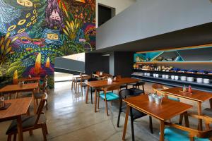 a restaurant with wooden tables and a colorful mural at ARTOTEL Gajahmada Semarang in Semarang