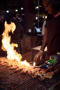 a man is cooking food on a grill with flames at Mercure Melbourne Therry Street in Melbourne