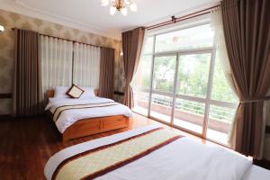 a bedroom with two beds and a large window at MINE Da Lat Hotel in Da Lat