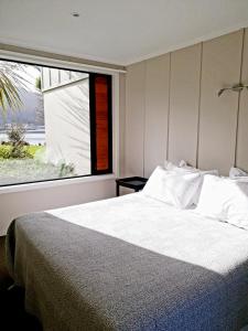 a bedroom with a large bed with a large window at Braxmere Lodge in Turangi