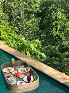 a tray of food on a table in the water at Anahata Villas and Spa Resort in Ubud