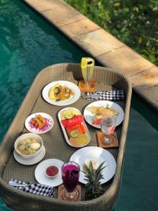 a table with plates of food on a boat in the water at Anahata Villas and Spa Resort in Ubud